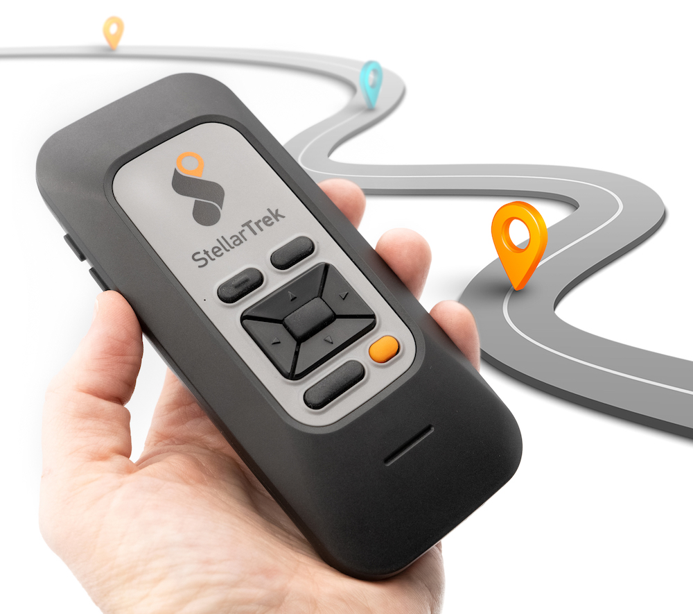 Humanware Stellar Trek, being held in a users hand, with a street in the background.